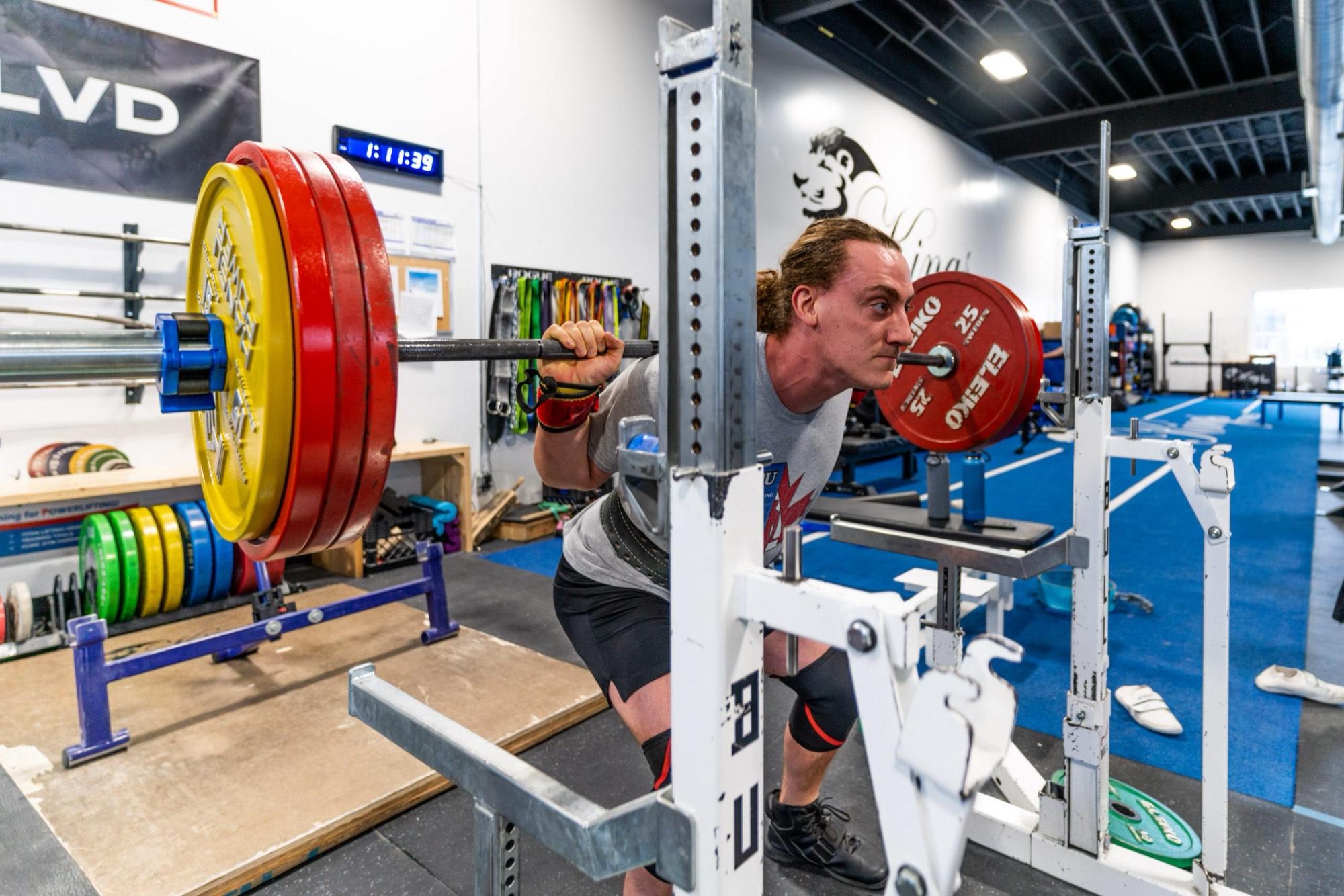 A powerlifter squatting heavy on an Olympic platform at Kings